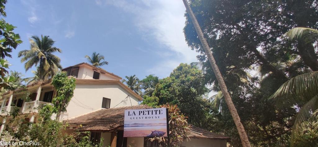 波戈马洛La Petite Guest House的棕榈树屋前的标志