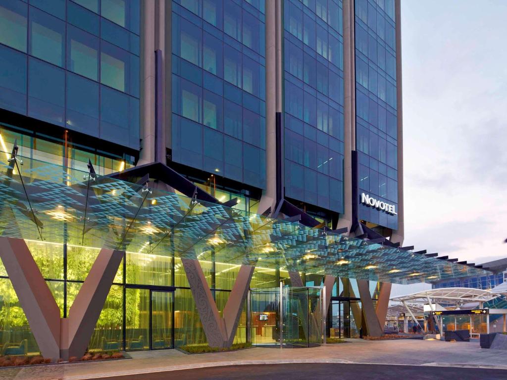 奥克兰奥克兰机场诺富特酒店的一座大型玻璃建筑,上面有标志