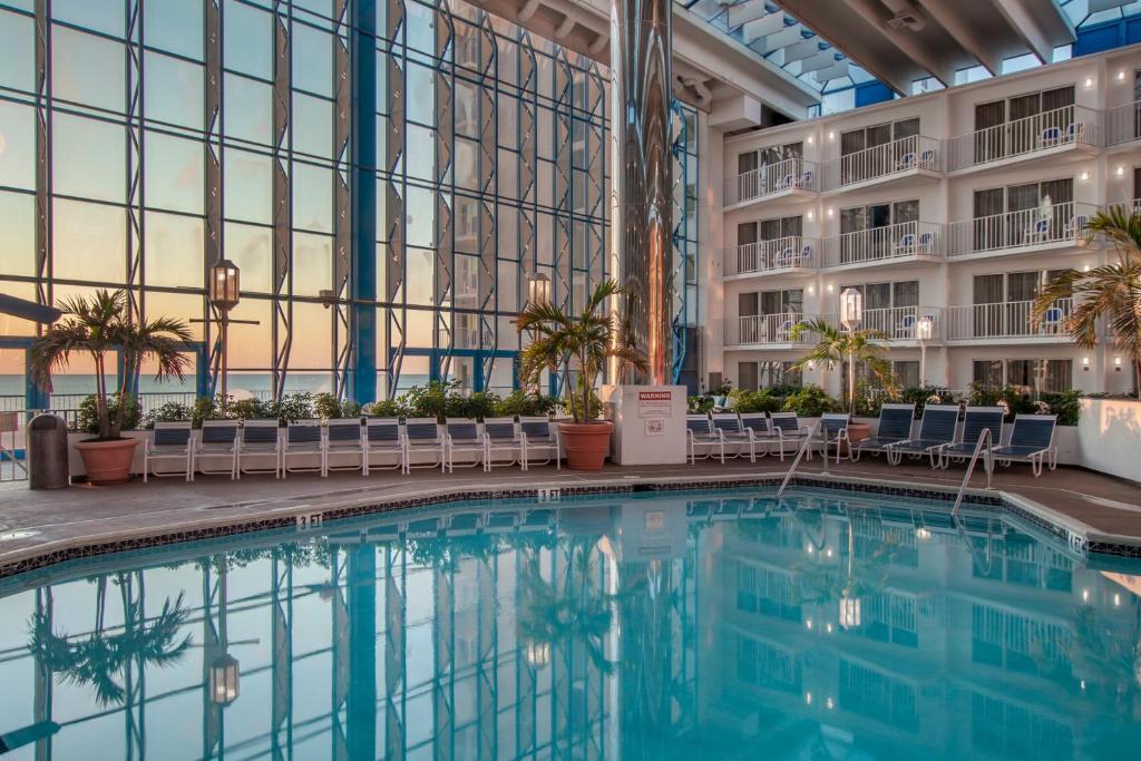 大洋城Princess Royale Oceanfront Resort的一座带椅子的酒店中庭和一座建筑中的游泳池