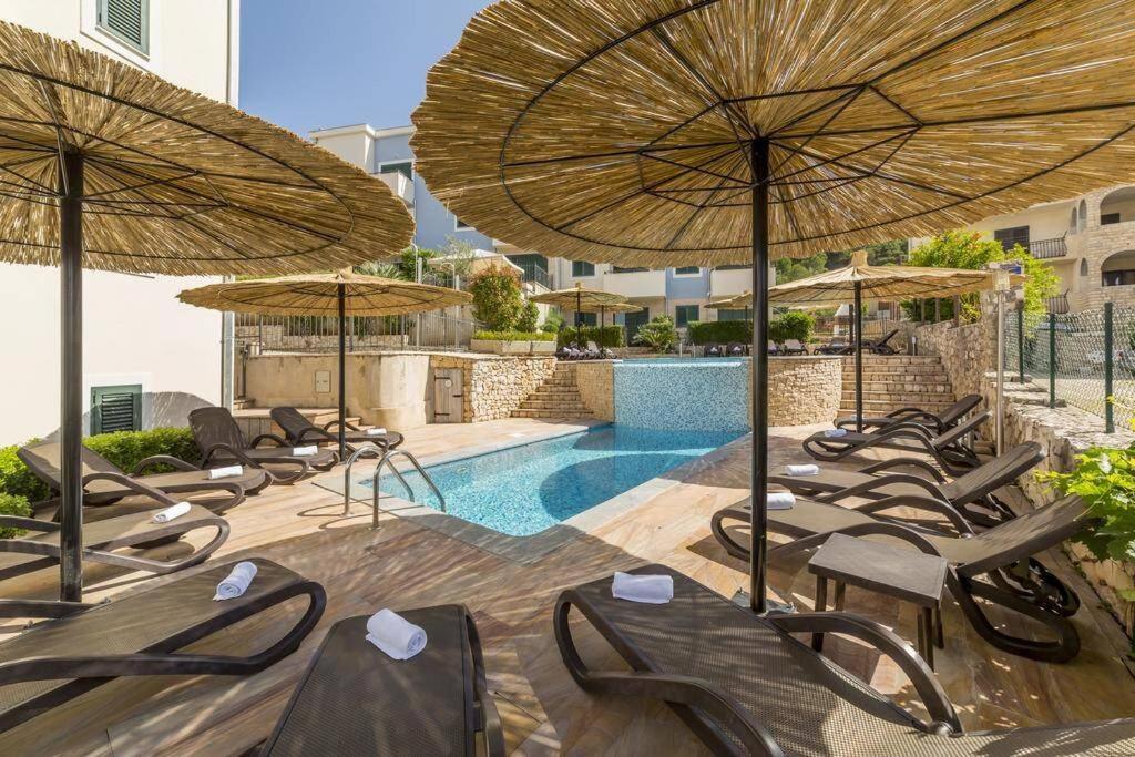 斯拉汀SeaEsta apartment Pool and Beach的一组椅子和遮阳伞,位于游泳池旁