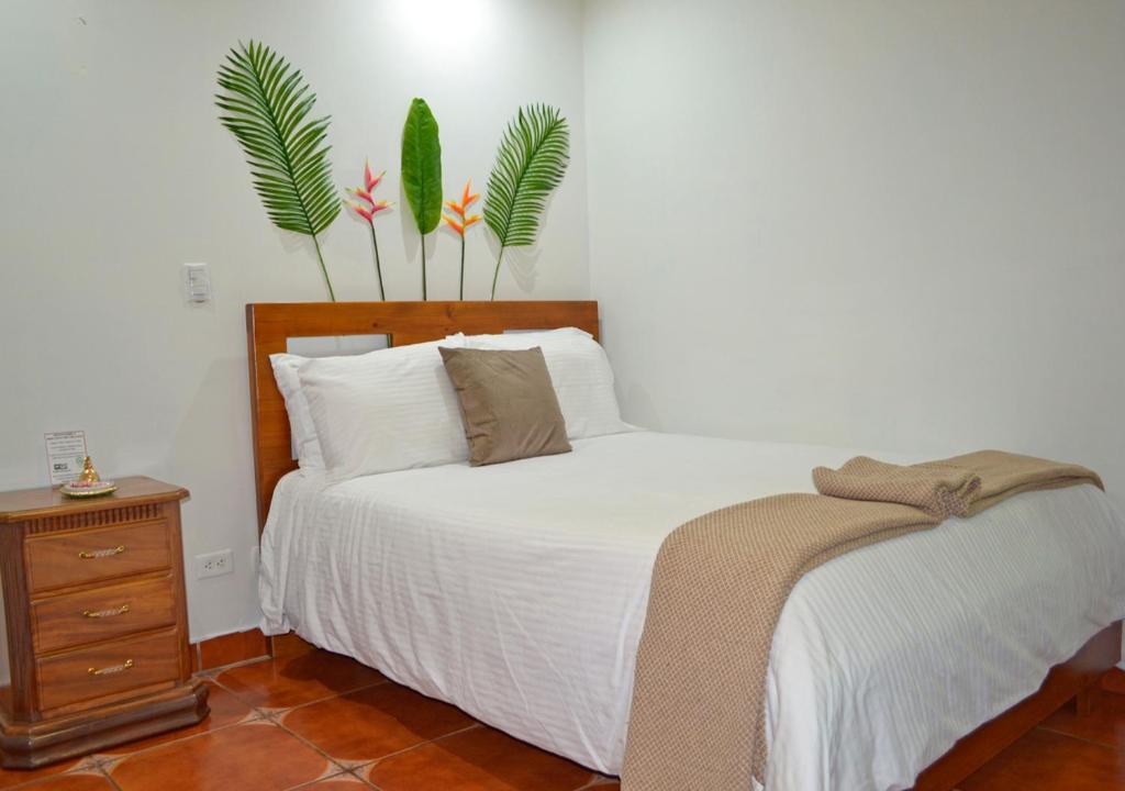 San JoaquínCasa Tropical的卧室配有一张床,墙上挂有两株植物