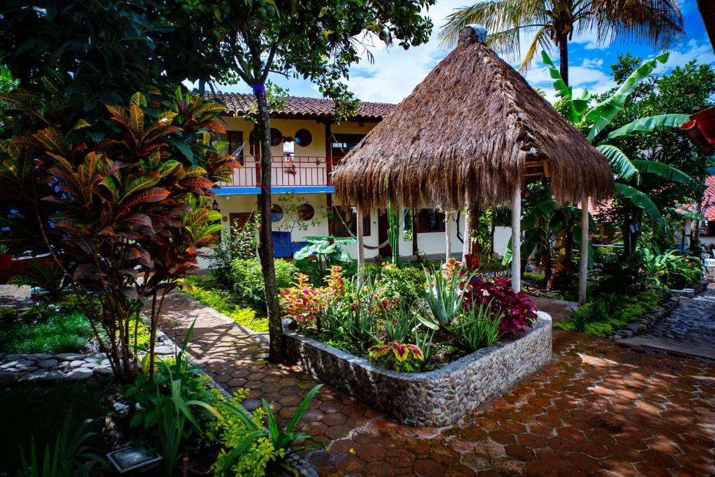 比尔卡班巴Hostal Jardín Escondido的一个带鲜花和茅草屋顶的花园的度假胜地