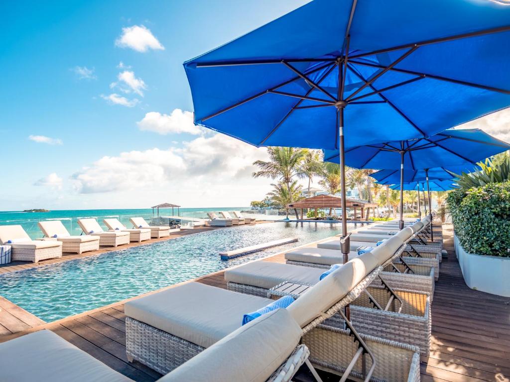 圣约翰斯Hodges Bay Resort & Spa的一个带椅子和遮阳伞的游泳池以及大海