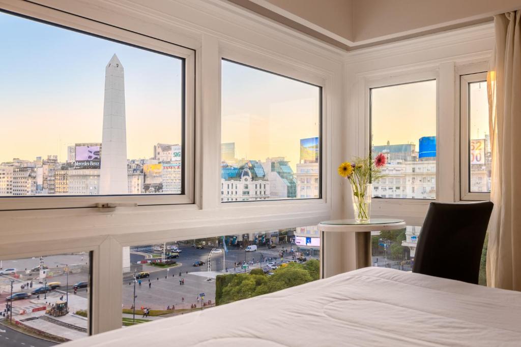 布宜诺斯艾利斯埃克科隆酒店的卧室设有大窗户,享有城市美景