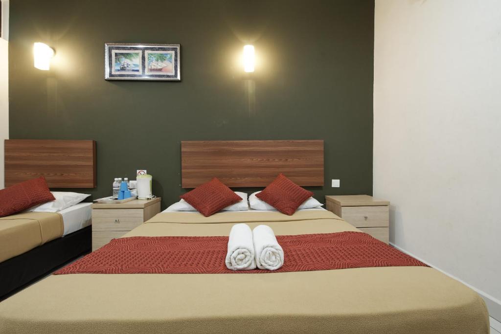 甘榜龙溪布城&赛城科普酒店的一间卧室配有一张大床,上面有白色毛巾