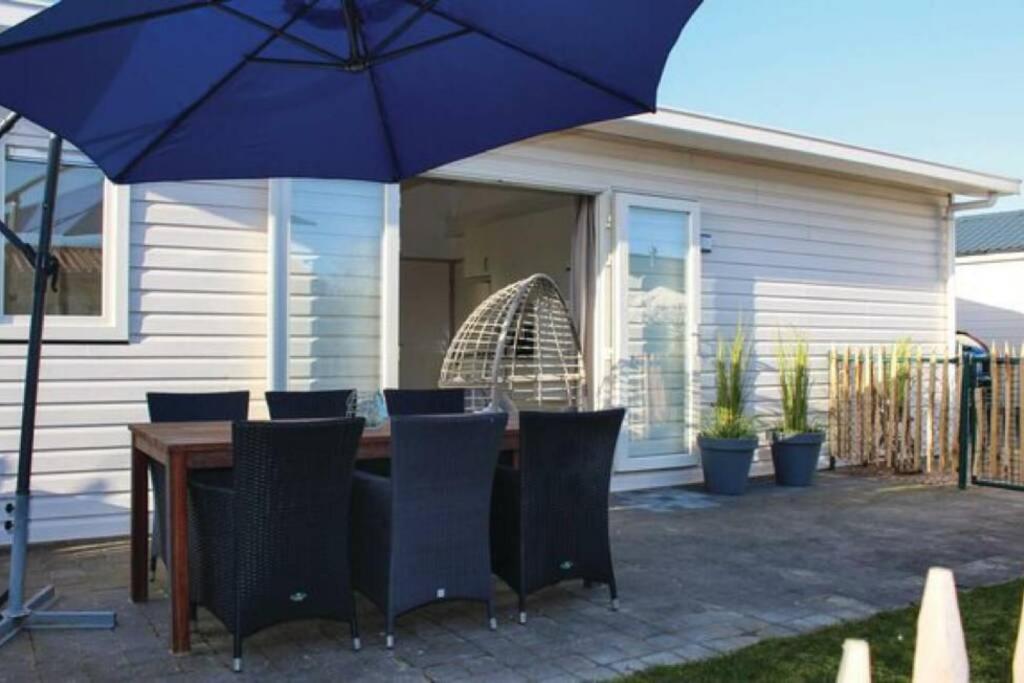 圣安娜兰Vakantie met sauna in Zeeland的一张桌子、椅子和蓝伞