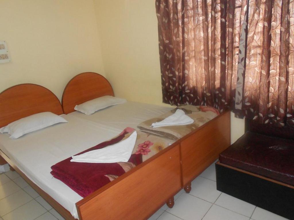 古瓦哈提Hotel Geetanjali的一间卧室配有一张带白色床单的木床