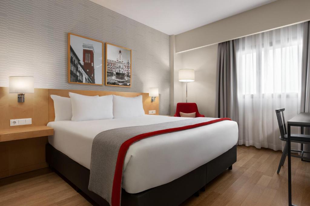 赫塔费Ramada by Wyndham Madrid Getafe的酒店客房设有一张大床和一张书桌。