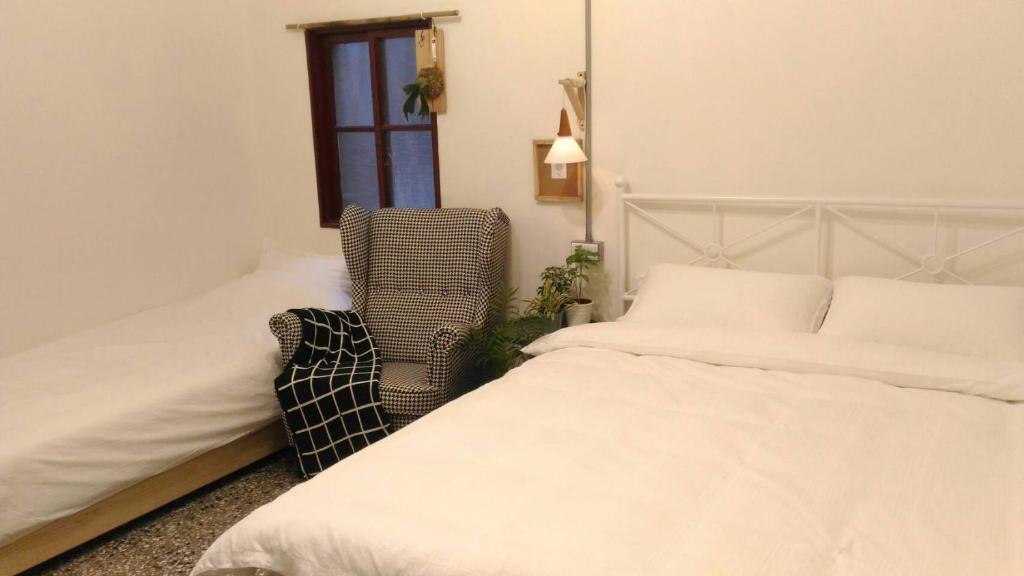 台南i老宅的一间卧室设有两张床、一把椅子和一个窗户。