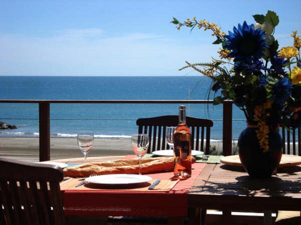 帕拉瓦莱弗洛Le Grand Large Bord de Mer Hotel & Appartements的一张桌子,上面有一瓶葡萄酒和眼镜,放在沙滩上