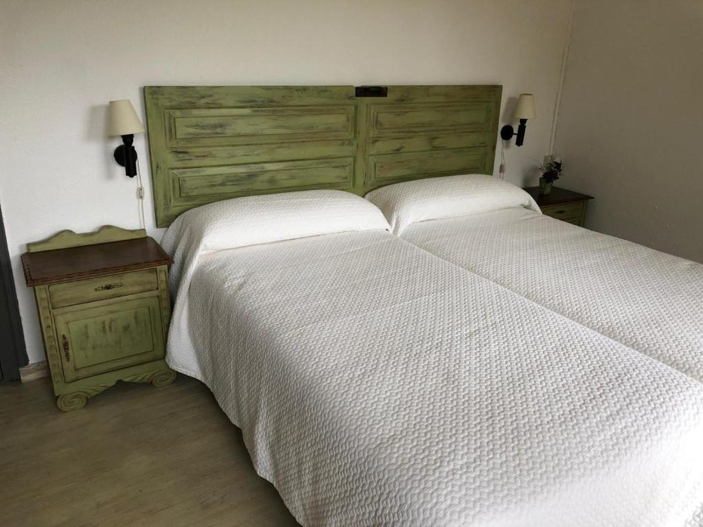 RuiseñadaCASA RURAL DOSAL的卧室配有白色大床和木制床头板