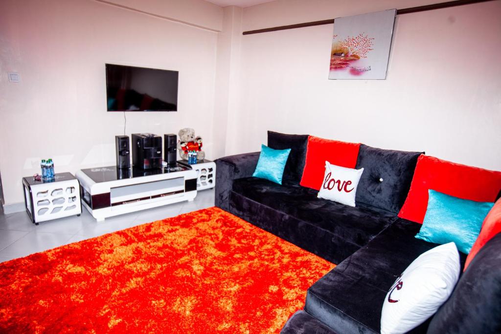内罗毕JJ Homes - Podium Heights Apartment Nairobi的客厅配有黑色沙发和红色地毯。