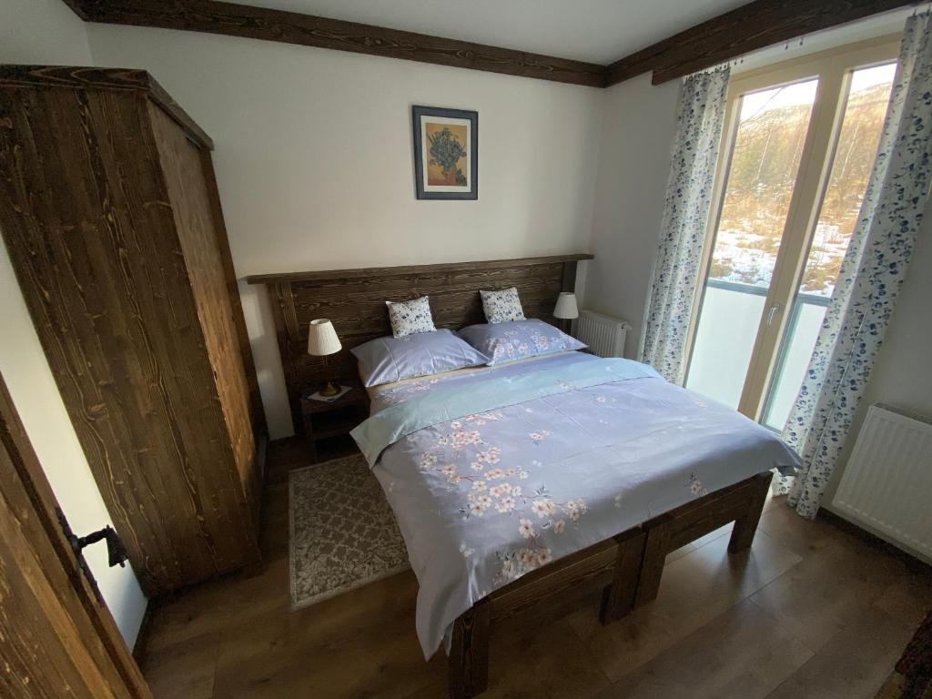 诺维斯莫克维克Apartmány Veternica v Bernarde的一间卧室配有一张带木制床头板的床和窗户。