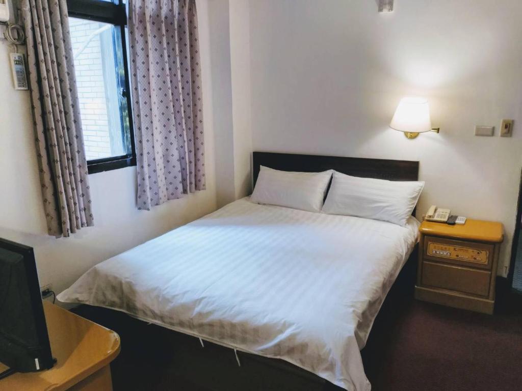 金宁乡金麗麗大飯店的一间卧室配有一张带白色床单的床和一扇窗户。