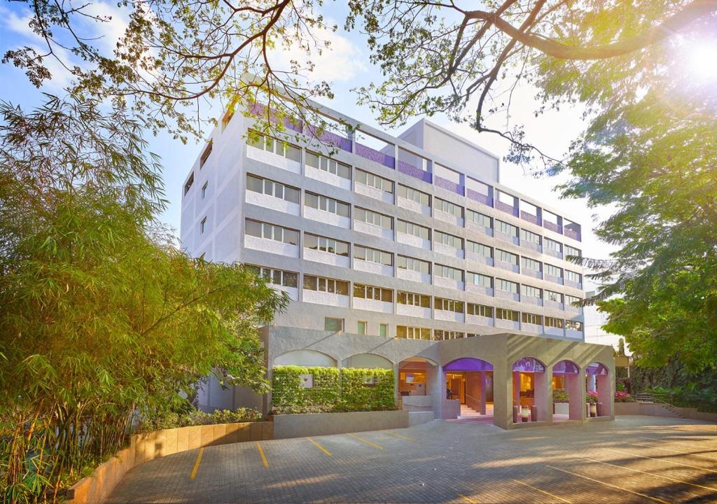 班加罗尔Vivanta Bengaluru Residency Road的一座白色的大建筑,前面设有停车场