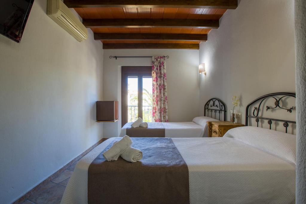 阿洛拉Hostal Valle Del Sol Alora的酒店客房设有两张床和窗户。