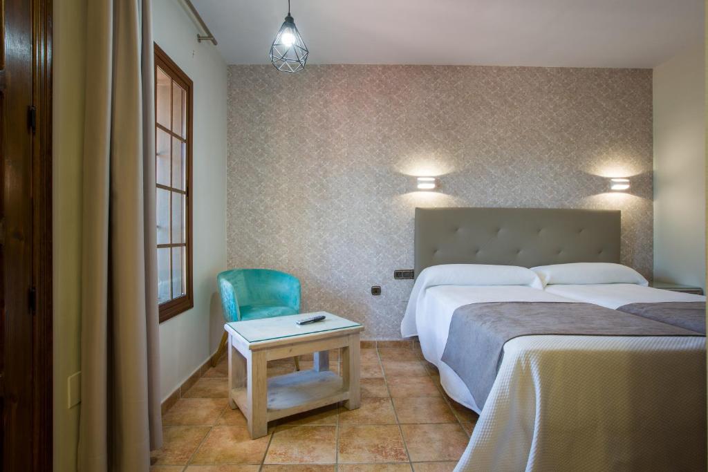 阿洛拉Hostal Don Joaquín Alora的一间卧室配有两张床、一张桌子和一把椅子