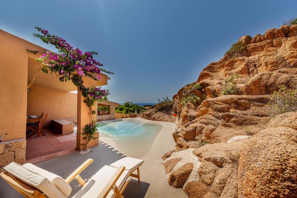 帕拉迪索海岸Costa Paradiso Resort的一个带椅子和岩石墙的游泳池