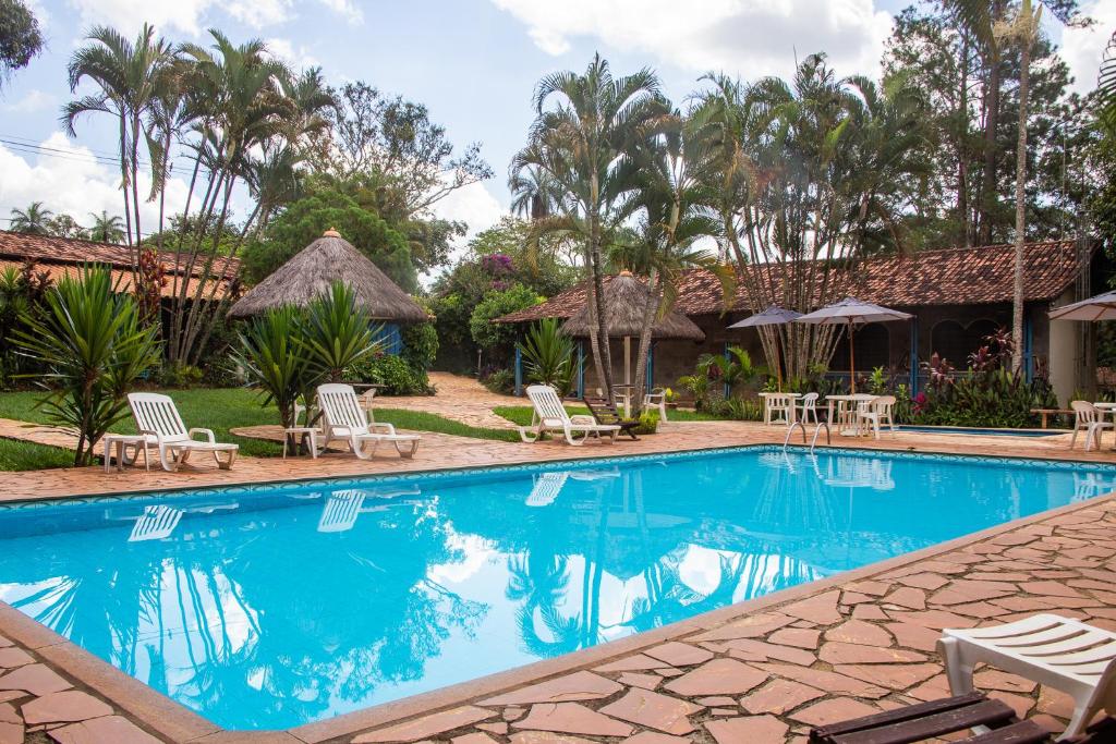 布鲁马迪纽Pousada Villa da Serra的度假村的游泳池,配有椅子和遮阳伞