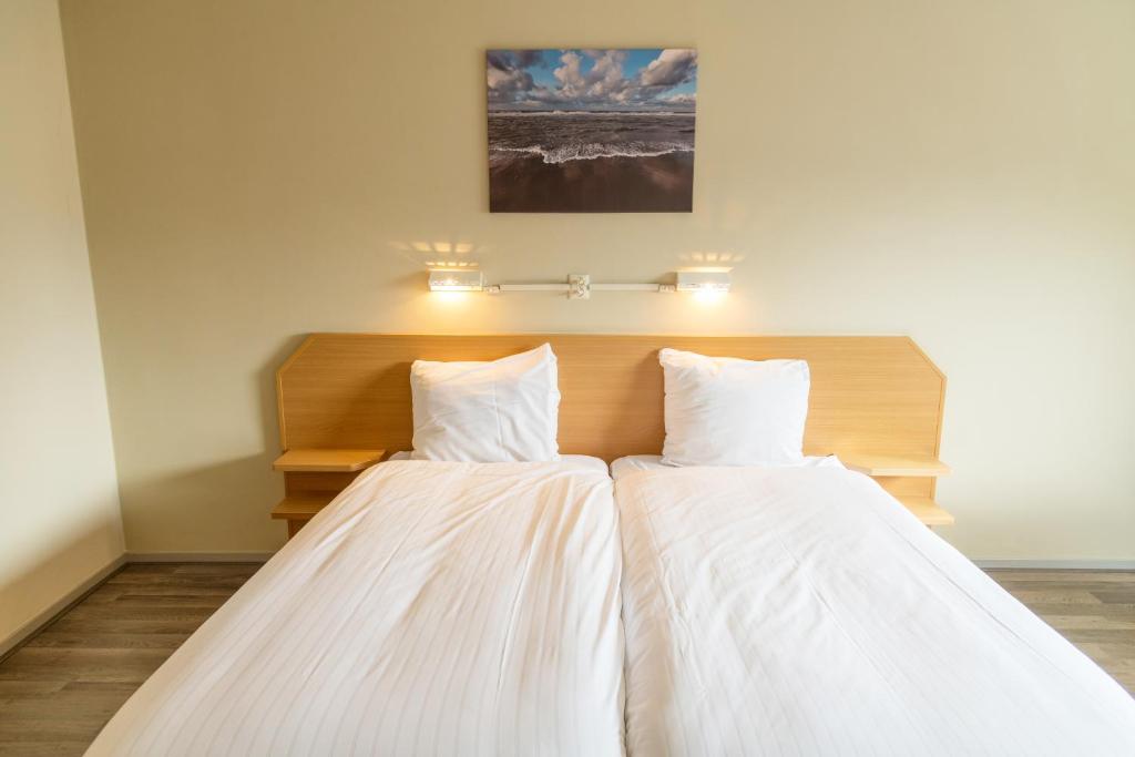 比尔弗利特德剑池波特酒店的一间卧室配有两张带白色床单的床