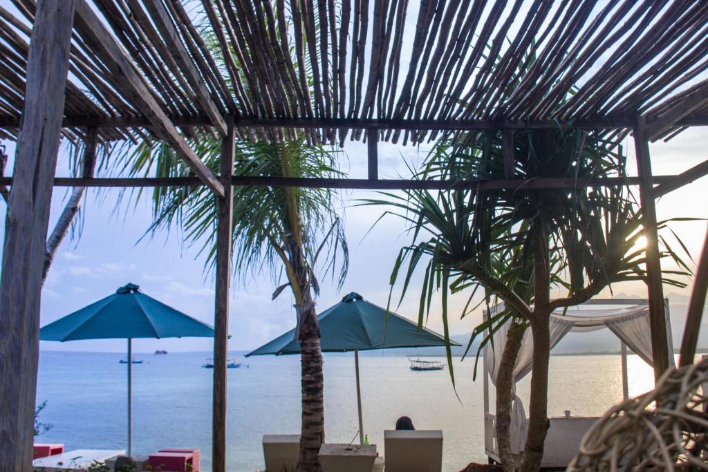 吉利阿尔卡鲁卡吉利度假酒店的享有海滩美景,配有遮阳伞和棕榈树