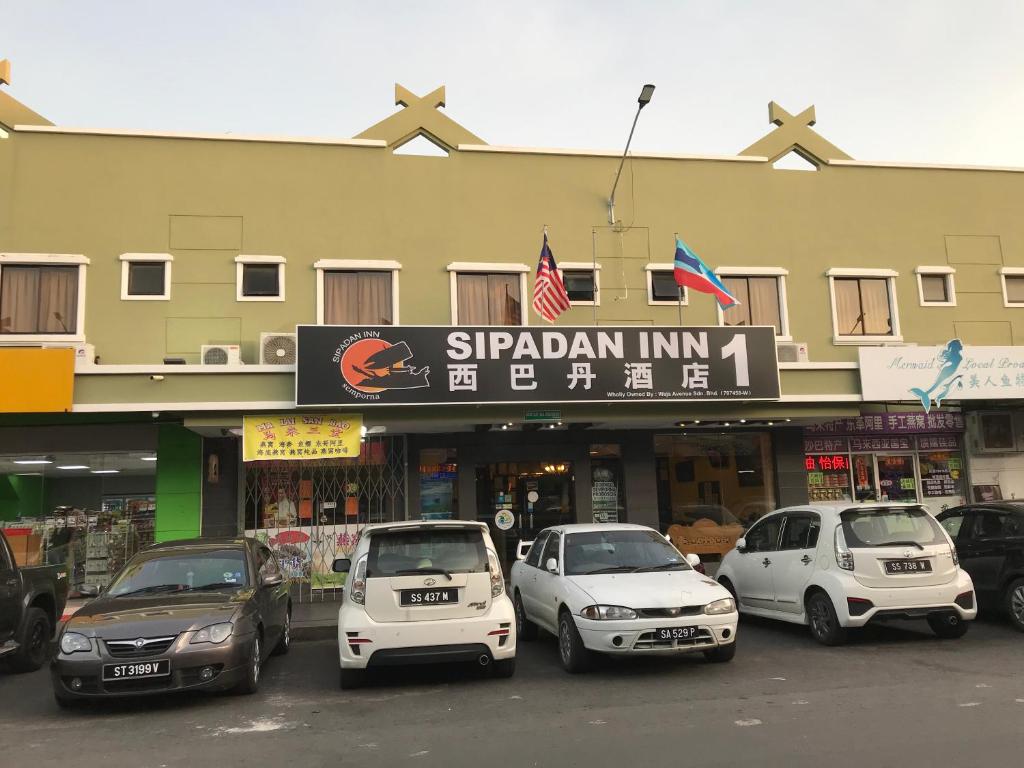 仙本那Sipadan Inn 1的停在大楼前的一组汽车