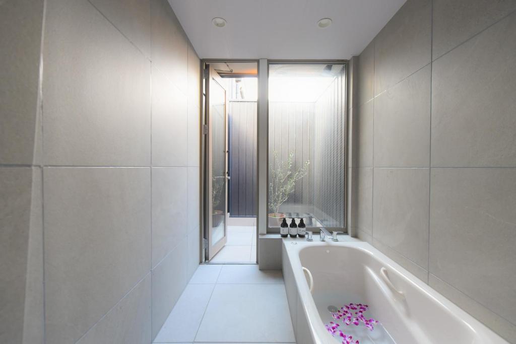 京都ホテル SHUNJU Rooji 1日1組様限定 近隣駐車場有的白色的浴室设有浴缸和窗户。