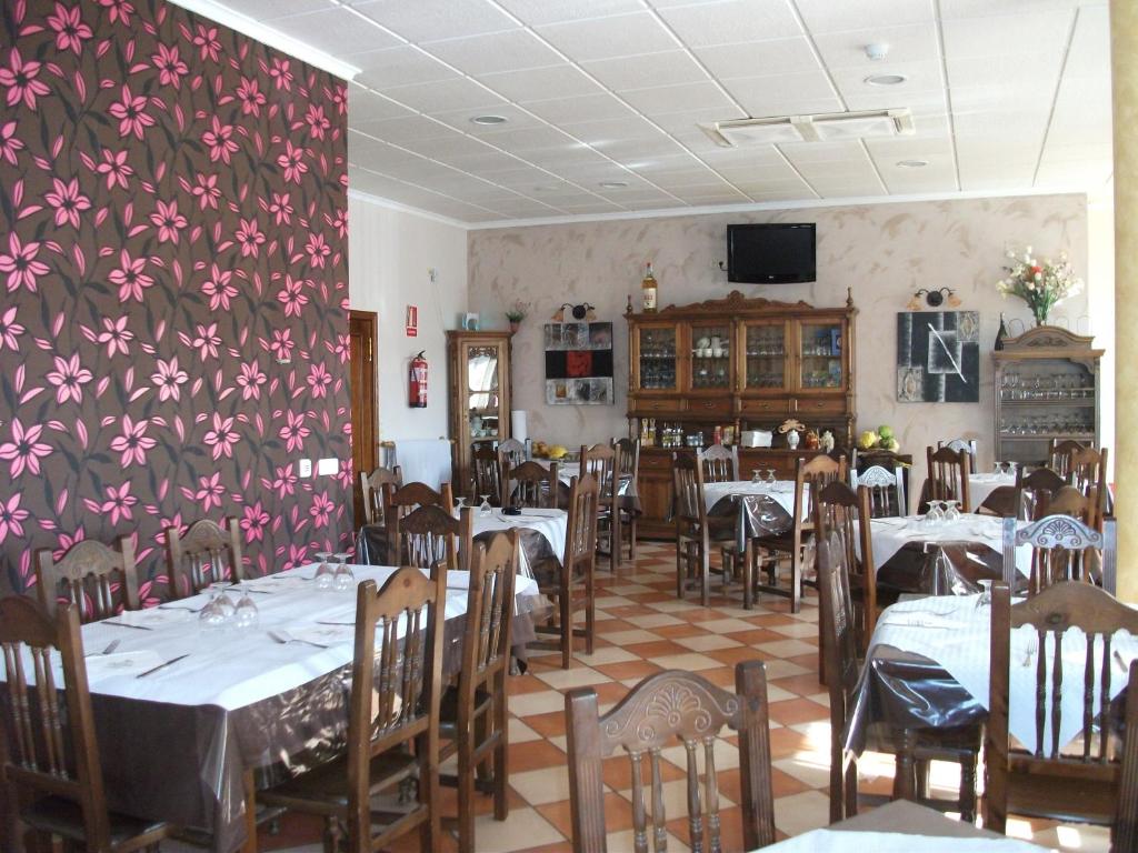 Carboneras de GuadazaónHostal Cabañas的餐厅设有桌椅和花卉墙