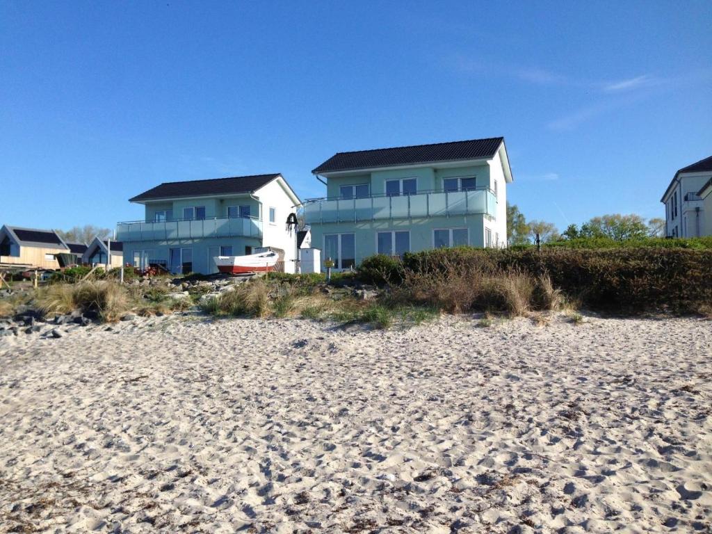 FehmarnsundStrandhaus-Appartment-Rauchschwalbe的沙滩旁的海滩上的房子