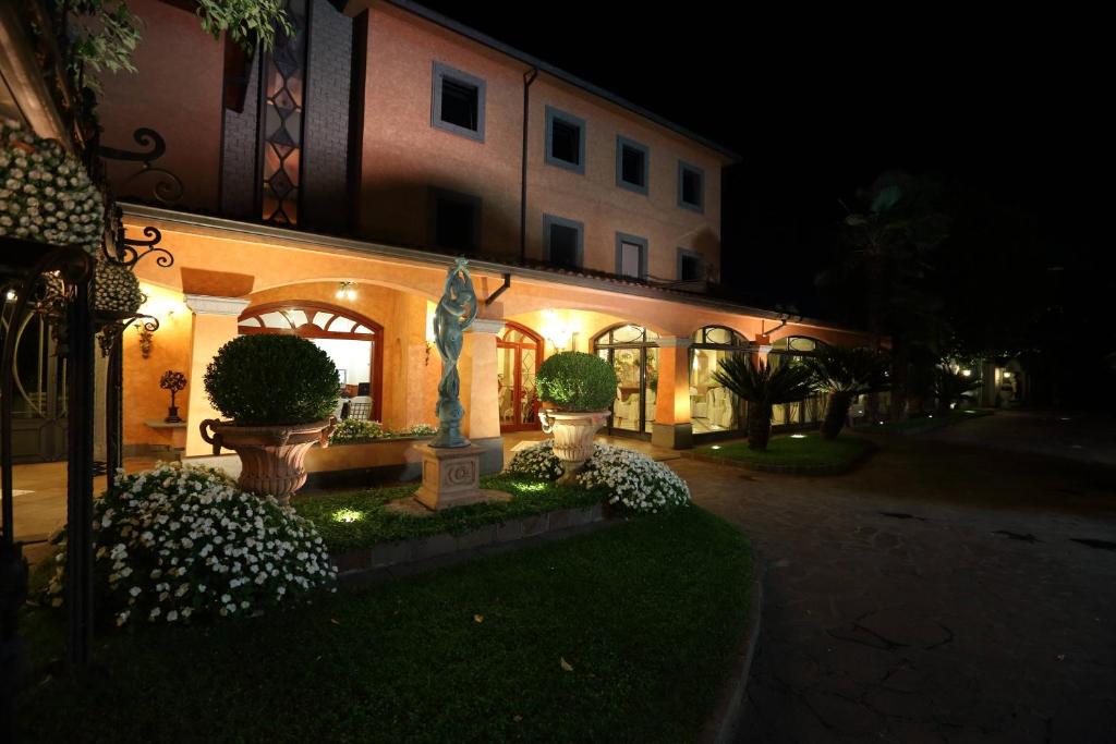 切普拉诺Hotel Ristorante Borgo Antico的一座建筑,在晚上有雕像在前面