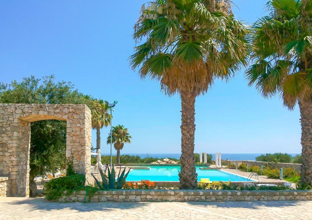 佩斯科勒海滨Picchio Hotel Pescoluse的度假村内棕榈树游泳池