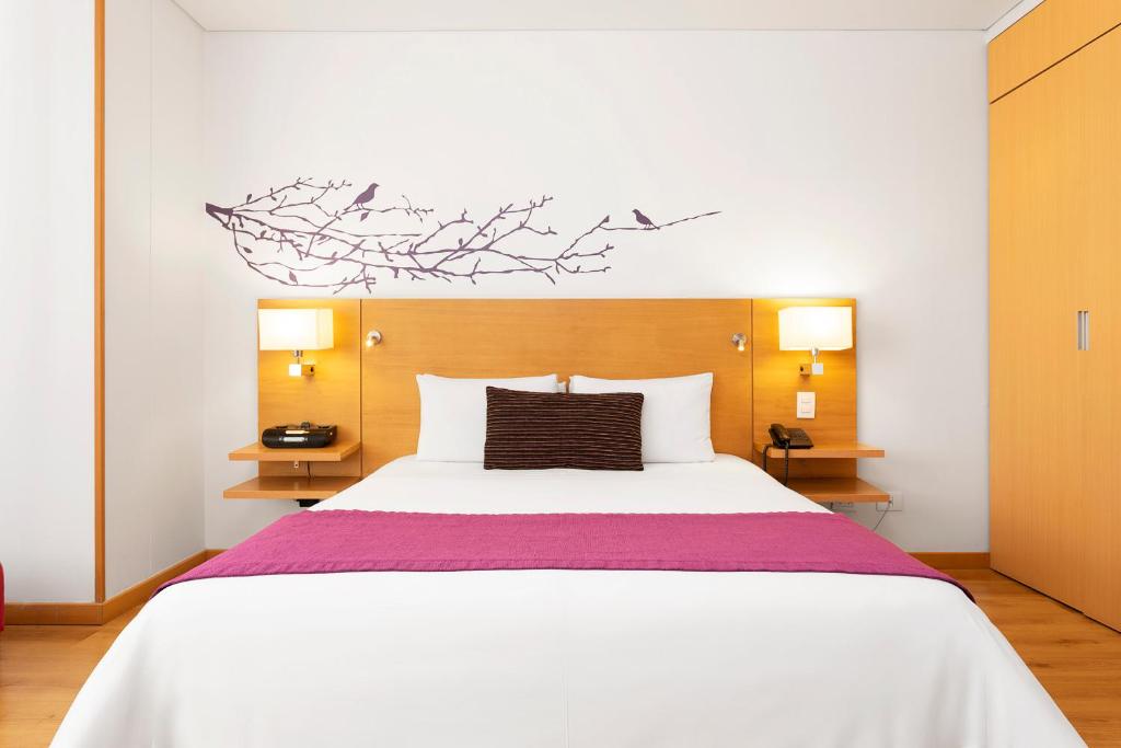 波哥大bh公园93号酒店的卧室配有一张白色大床和两盏灯。