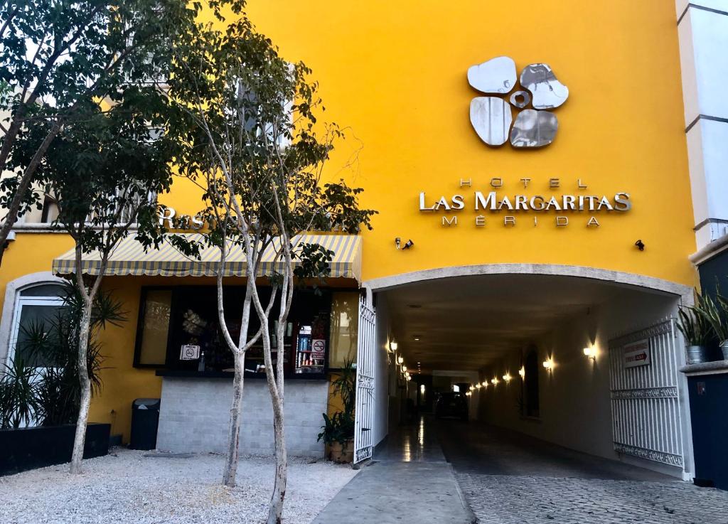 梅里达Hotel las Margaritas Merida的一座黄色的建筑,上面有读过马里奥特的标志