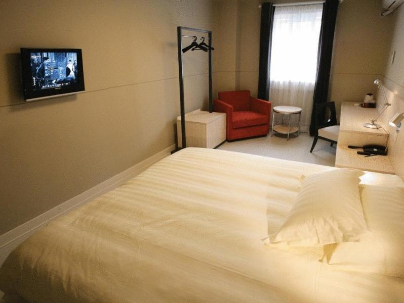 上海锦江之星上海长宁店的卧室配有一张白色大床和红色椅子