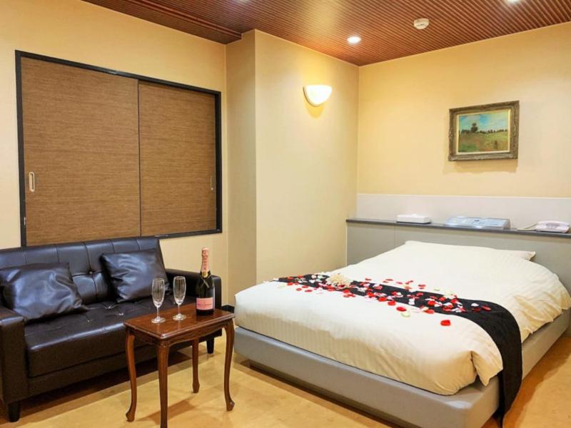 东京Hotel NewMie (Adult Only)的一间卧室配有一张床、一张沙发和一张桌子