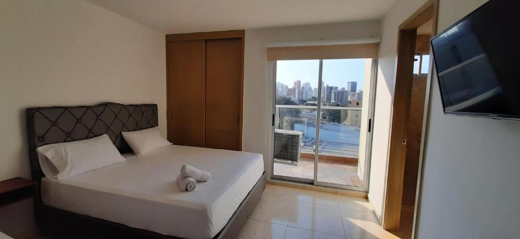 巴兰基亚Apartahotel Plaza de ángel 74的一间卧室设有一张床和一个大窗户