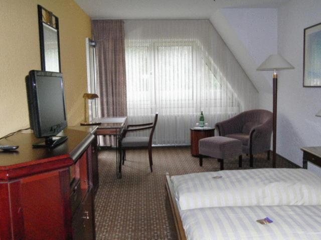 摩泽尔肯Hotel Moselkern的酒店客房配有一张床和一张书桌及一台电视