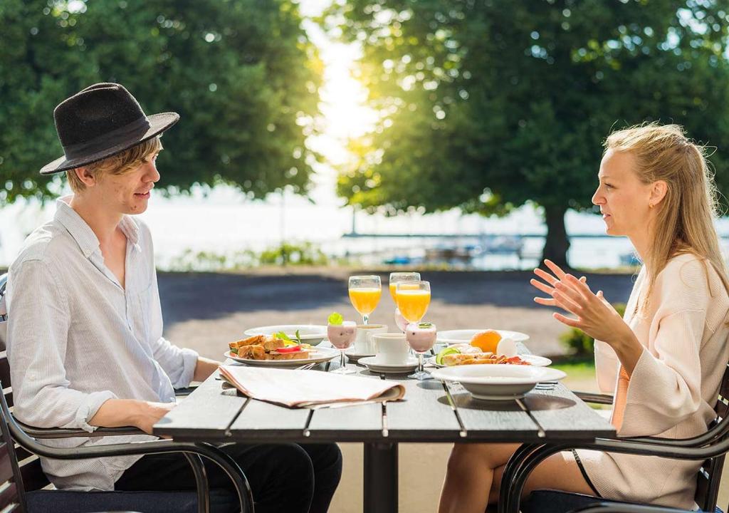 尤城Hotel Bellevue的两人坐在桌子旁,一边享用食物和饮料
