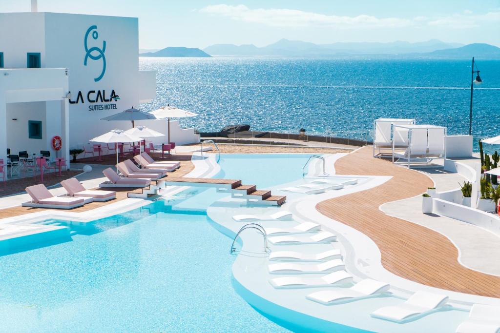 普拉亚布兰卡CalaLanzarote Suites Hotel - Adults Only的游泳池的 ⁇ 染,游泳池的椅子和海洋