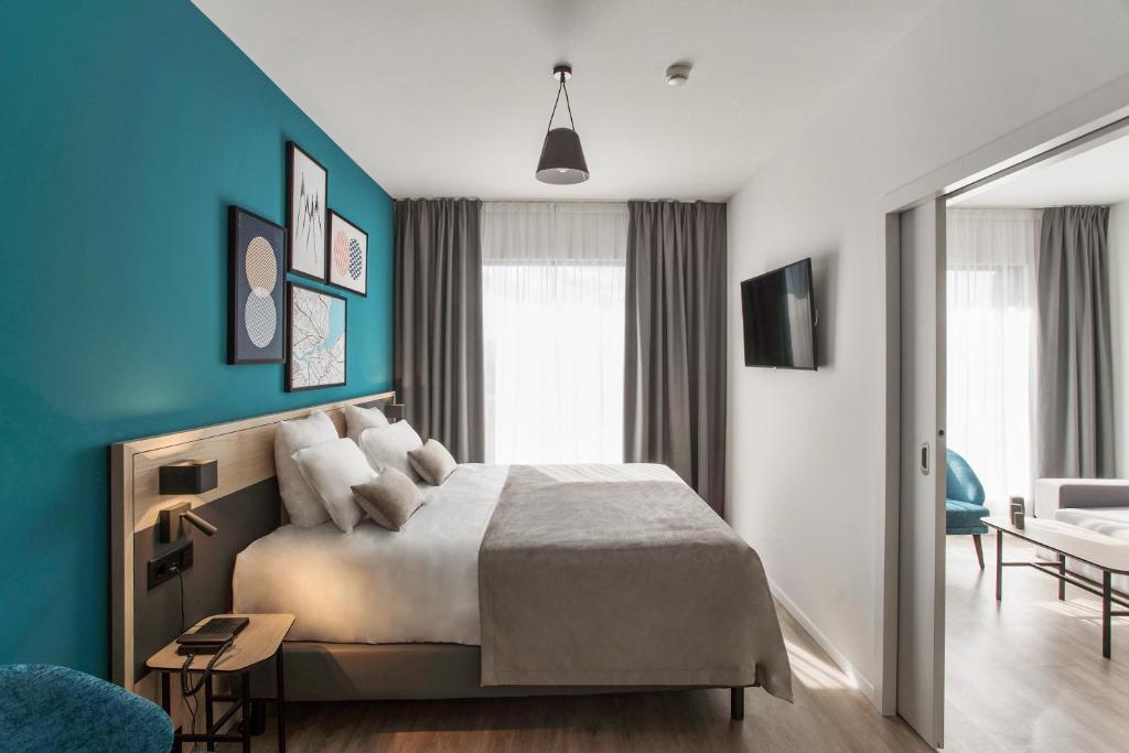 日内瓦Appart'City Collection Genève Aéroport - Vernier的一间卧室设有一张床和蓝色的墙壁