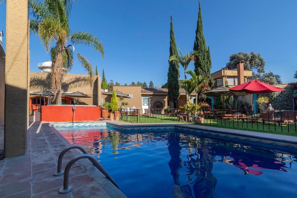 乔卢拉Capital O La Huerta Golf & Hotel的一座棕榈树游泳池和一座房子