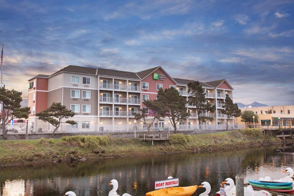 西塞德海滨会展中心快捷假日&套房酒店的一群天鹅在水中,站在酒店前