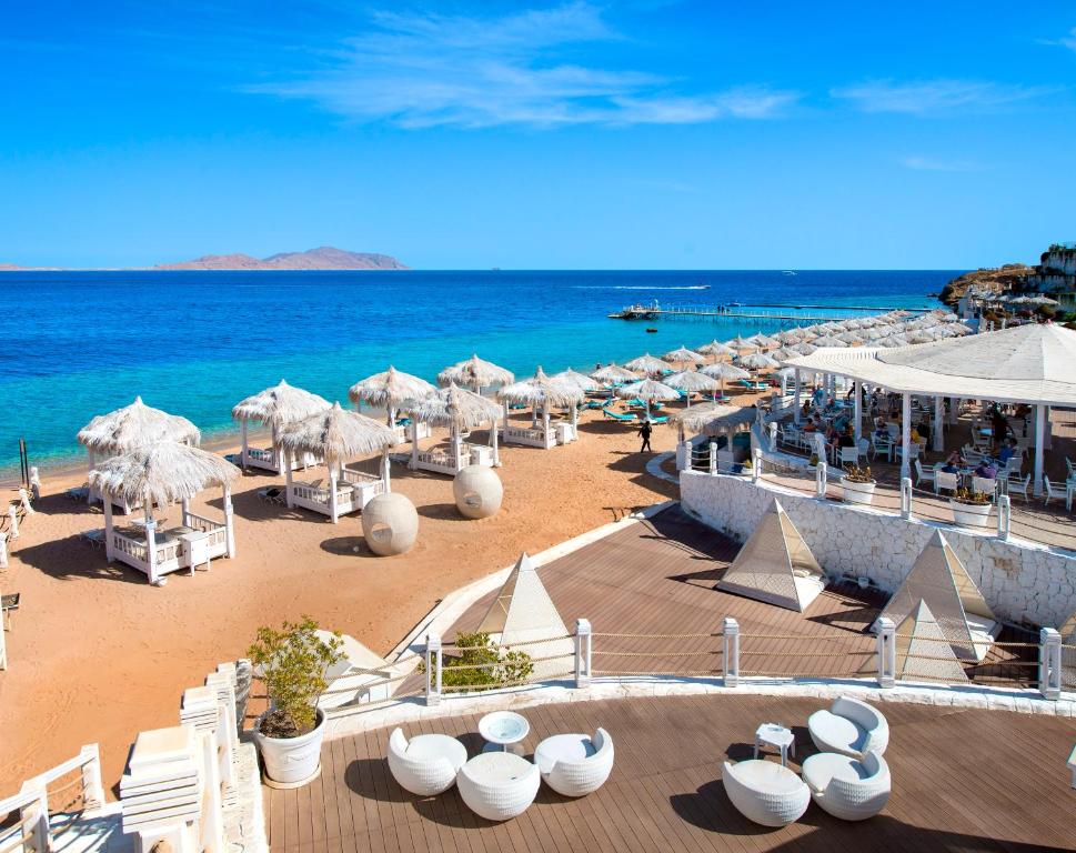 沙姆沙伊赫Sunrise Arabian Beach Resort的海滩上设有椅子和遮阳伞,还有大海