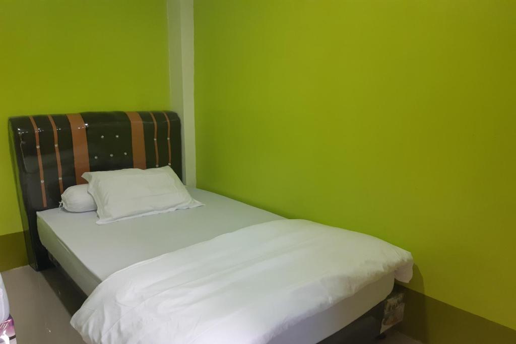 LubukpakamOYO 3487 Es Em Je Residence的绿色的小房间,配有白色床单