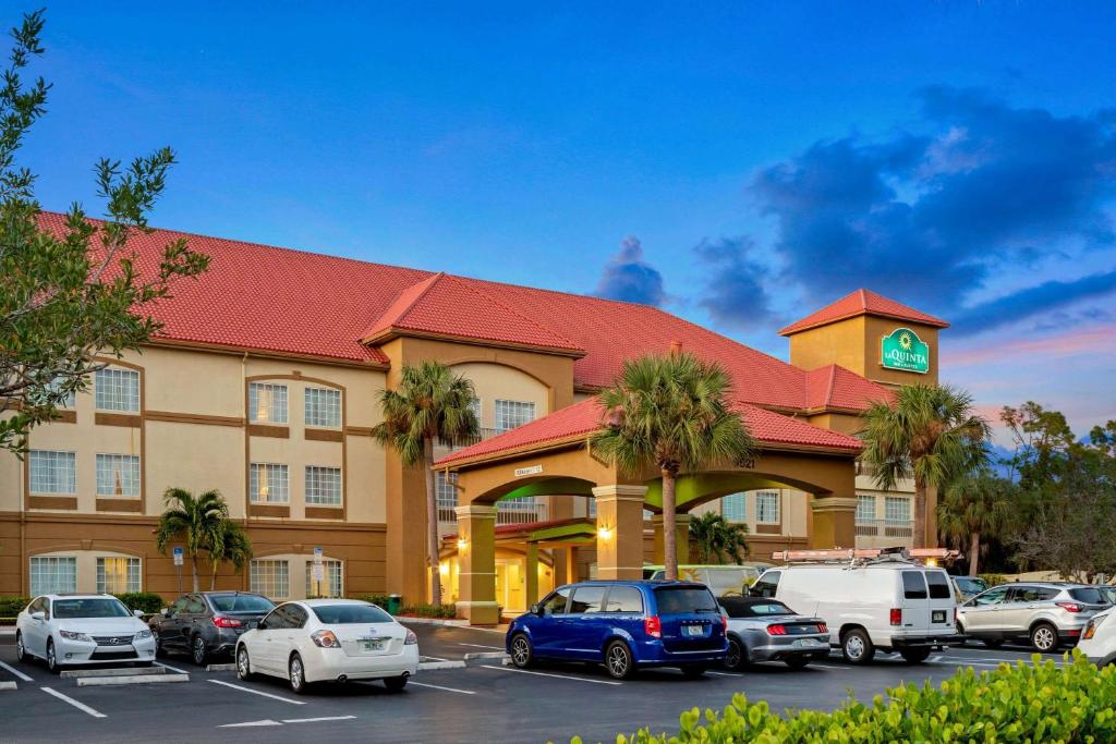 迈尔斯堡La Quinta Inn and Suites Fort Myers I-75的停车场内有车辆的旅馆