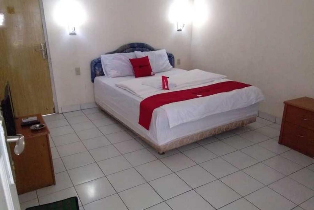 TenjoRedDoorz near Lokawisata Baturaden 2的一间卧室配有一张带红色和白色枕头的大床