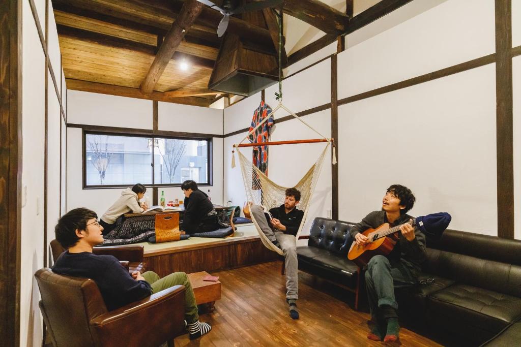 松本Couch Potato Hostel的一群坐在一个房间里弹吉他的人