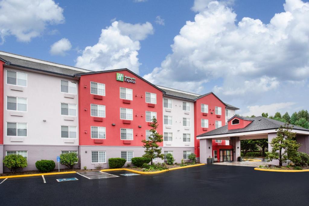 林肯市Holiday Inn Express & Suites Lincoln City, an IHG Hotel的停车场内有红白色建筑的酒店