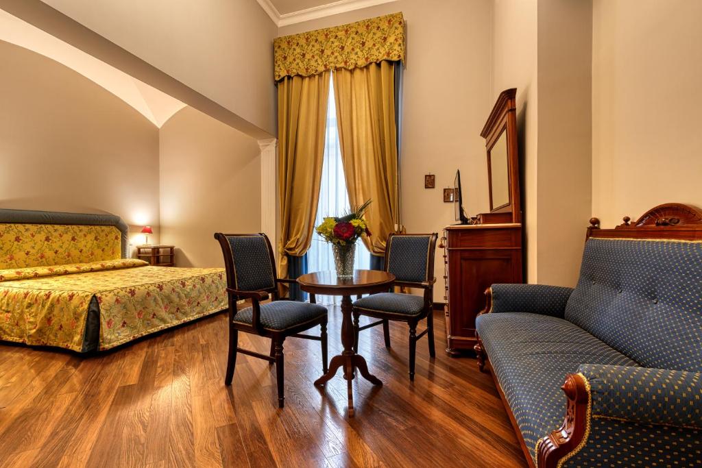 那不勒斯德库玛德尼查梅酒店的卧室配有一张床和一张桌子及椅子
