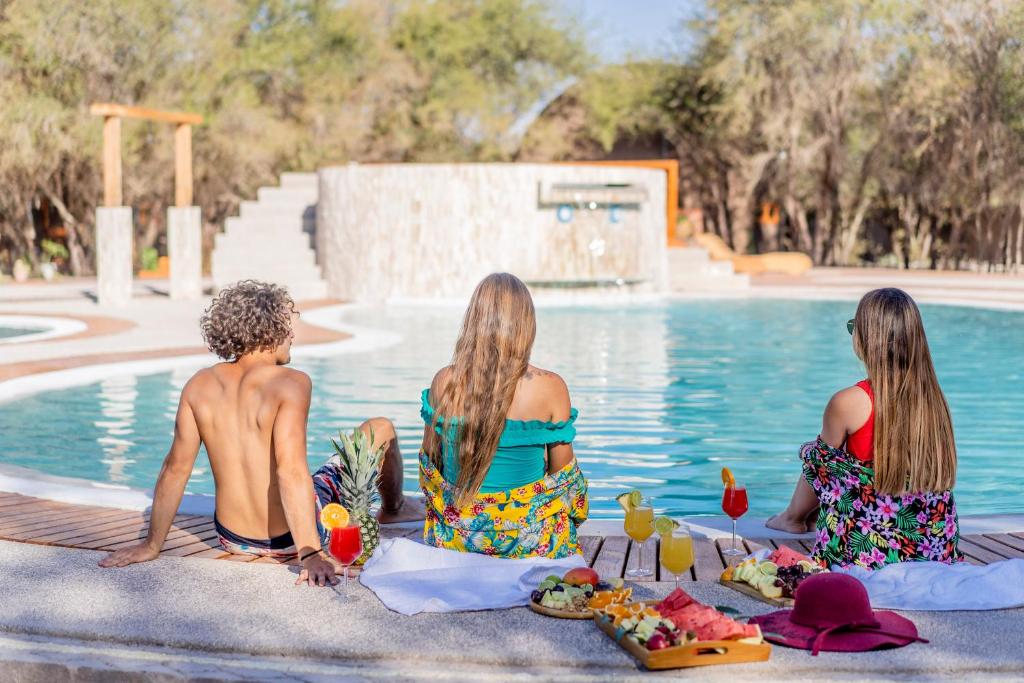 La HuaicaTantakuy Eco Experience Hotel的一群坐在游泳池旁的三个女孩